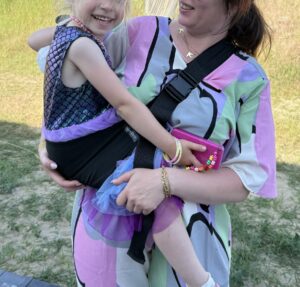 Mama nosi dziecko w nosidełku biodrowym DereDere