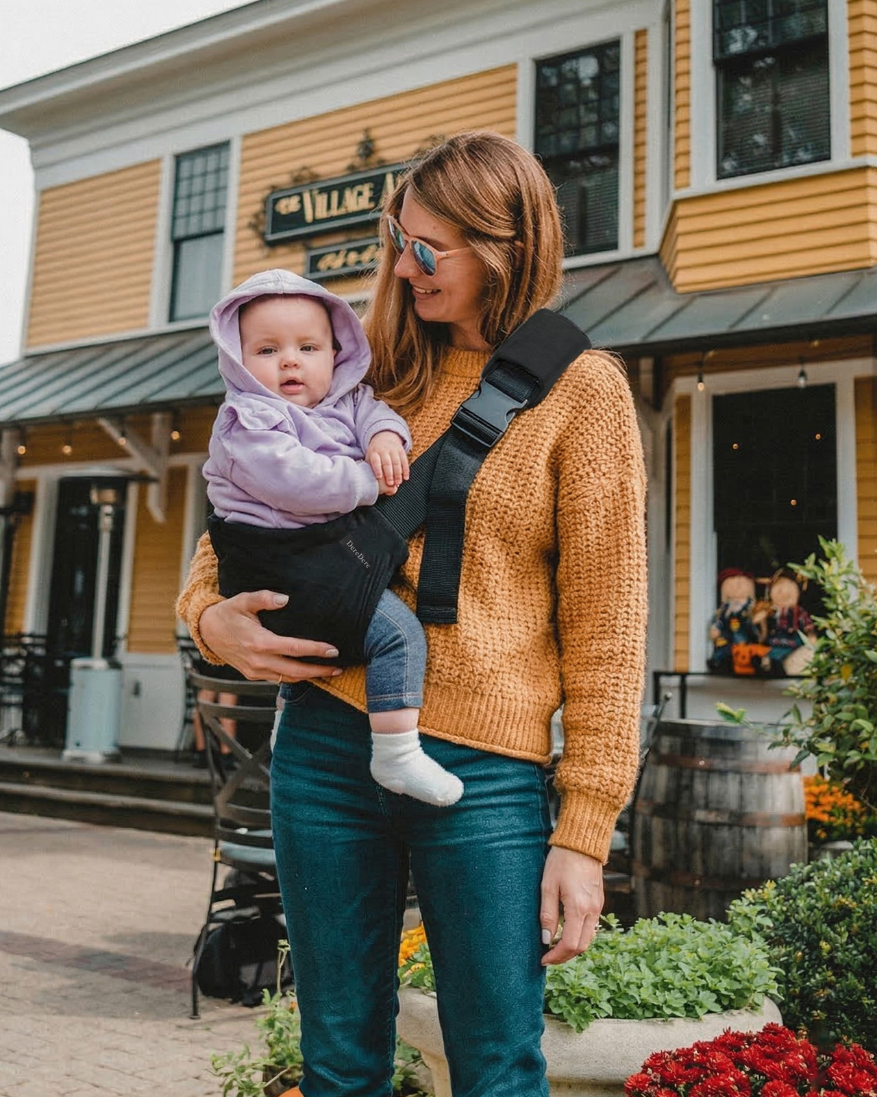 Nosidełko na biodro DereDere mama niesie dziecko na biodrze podczas spaceru w mieście
