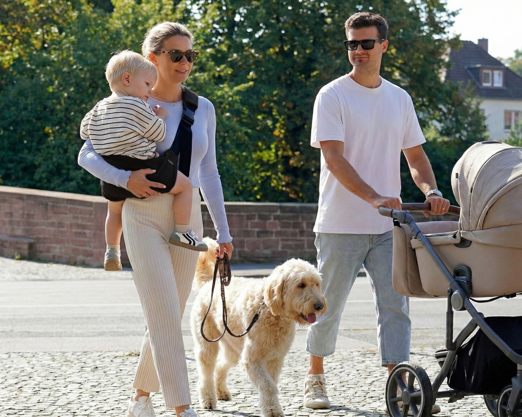 Mama niesie dziecko w czarnym nosidełku DereDere podczas rodzinnego spaceru.